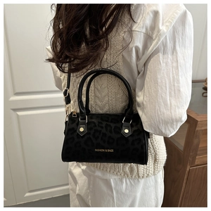 Detail of black leopard print Boston bag with gold brand lettering and hardware