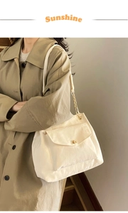 Detail of off-white tote bag featuring a gold twist lock and metal chain strap