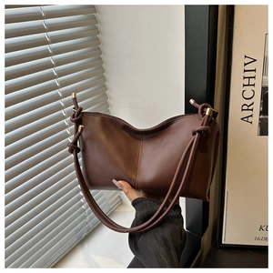 Detail of coffee brown leather shoulder bag with V-shaped curve and gold hardware