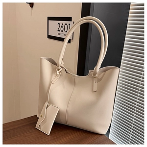 Detail view of beige leather tote bag with matching coin purse on a wooden table