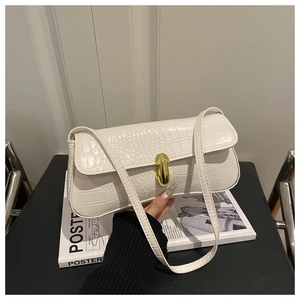 Close-up of beige crocodile pattern handbag with elegant gold metal twist lock buckle