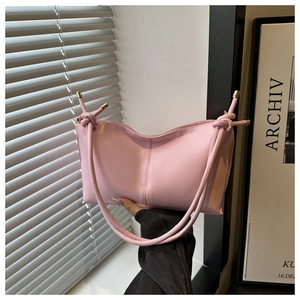 Close-up of pink crescent tote with knot handle and golden metallic details