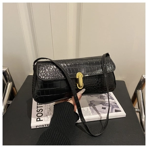 Close-up of black crocodile-embossed baguette bag with stylish golden twist lock clasp