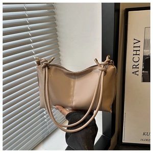 Detailed view of beige faux leather tote bag with round cord straps and gold metal tips