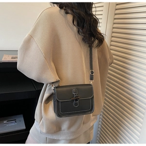 Detail of vintage black messenger bag with horn buckle and white contrast stitching