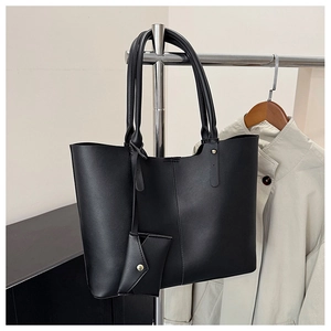 Close-up of black leather tote bag with vertical stitching and matching coin purse detail