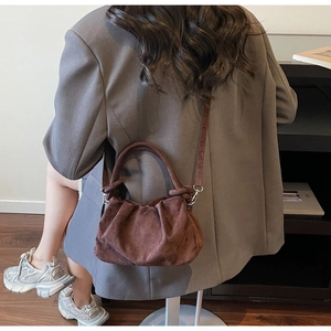 Rear view of woman carrying brown suede cloud bag with soft pleated texture and strap