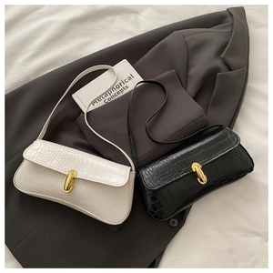 Detail of elegant crocodile embossed faux leather baguette bags with golden metal clasps