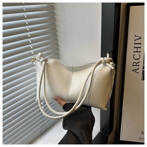 Close-up of knotted cylindrical straps with gold metal tips on a white tote bag