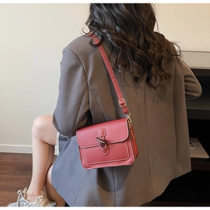Detailed view of red retro square crossbody bag with contrast stitching on a model