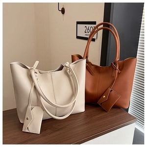 Close-up of cream and brown leather tote bags with matching pouches on a wooden surface
