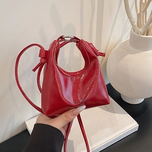 Red patent leather hobo handbag with logo in a minimalist stylish lifestyle setting
