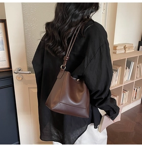 Deep brown leather bucket bag detail showing matte texture and knotted shoulder strap