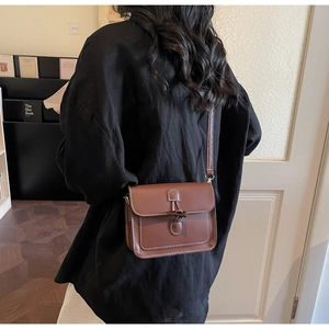 Detailed view of vintage brown leather crossbody bag with toggle closure on model