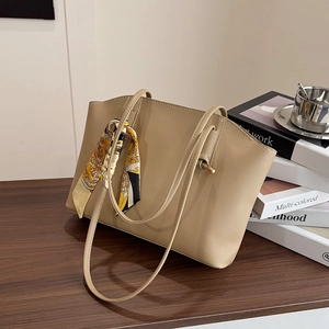 Elegant beige tote bag with decorative silk scarf on a stylish wooden desk background