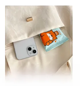 Detail of the front storage pocket on a beige ruched shoulder bag holding a smartphone