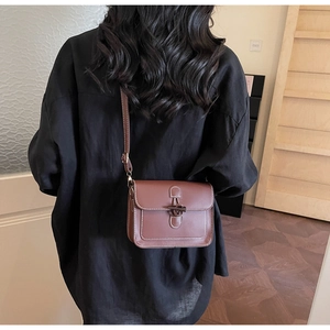 Rear view of brown vintage leather crossbody bag with toggle closure on a female model
