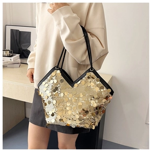 Close-up of golden sequins on large tote bag with black trim and elegant shoulder straps