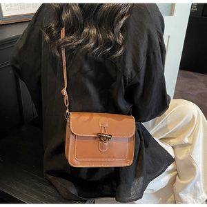 Detail of brown vintage messenger bag with toggle button and contrast stitching