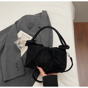 Detailed texture of black pleated faux suede handbag with silver metal hardware accents