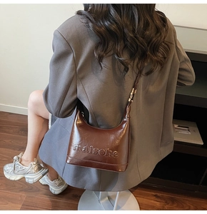 Detail of dark brown matte leather hobo bag with embossed lettering on model