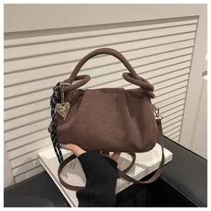 Detail of coffee brown suede handbag with thick rope knot handle and golden heart charm