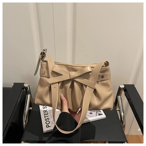 Detail der beigen Plissee-Schultertasche mit Schleife und Metall-Sternnieten