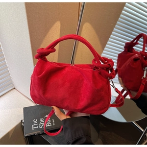 Detail of red faux suede handbag showing pleated design and unique knot handle detail