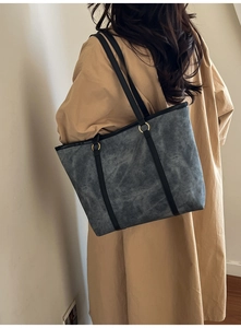 Détail du grand sac cabas gris texturé avec des lanières noires sur un mannequin femme