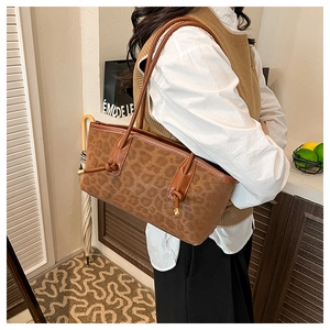 Detail of a brown leopard print tote bag with adjustable shoulder strap and gold hardware