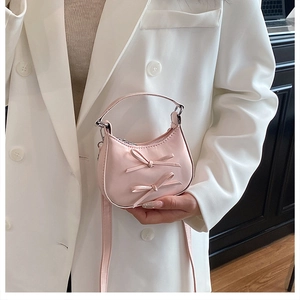 Détail du sac à main demi-lune rose avec nœuds et bandoulière élégante pour femme