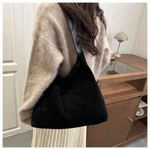Detail einer schwarzen Hobo-Tasche aus Wildleder mit Seitentaschen und feinen Nähten