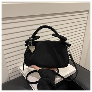 Detail of vintage black velvet handbag featuring pleated flap and silver heart pendant