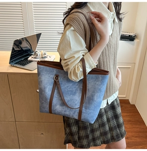 Détail du sac cabas en denim bleu avec garniture en cuir marron et anneaux en métal