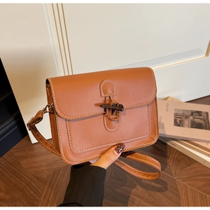 Close-up of brown PU leather bag with dark wood toggle closure and white stitching