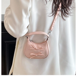 Close-up of pink mini crossbody bag featuring sweet bow accents and silver hardware