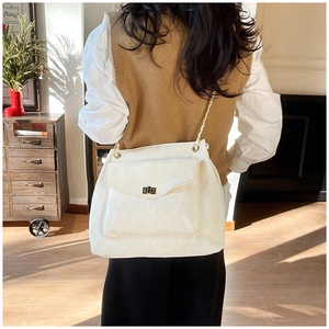 Detail of cream leather tote bag featuring a gold twist lock pocket and chain strap detail