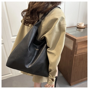 Detailed side view of a black PU leather tote bag with gold Fashion text on shoulder