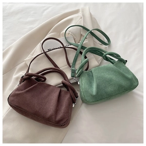 Detail of soft suede-like crossbody bags in brown and green with ruched design textures
