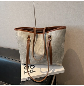 Détail du cabas en toile bleu gris avec anses en cuir marron et anneaux dorés en métal
