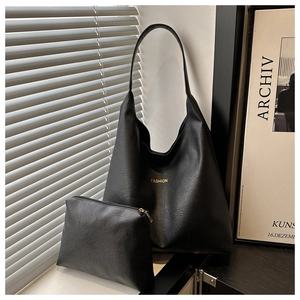 Close-up of black leather hobo bag and matching pouch with gold FASHION lettering