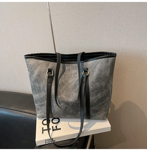 Détail du sac cabas gris texturé avec anses en cuir noir et anneaux métalliques dorés