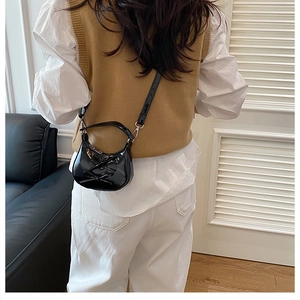 Vue détaillée du dos d'un sac demi-lune en cuir verni noir avec nœud décoratif