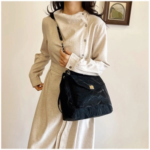 Detail of black textured tote bag with golden twist lock and metal chain strap