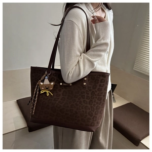 Dettaglio della borsa tote leopardata con finiture in pelle marrone e placca oro