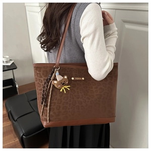 Dettaglio della borsa tote leopardata con logo dorato e ciondolo orsetto ricamato