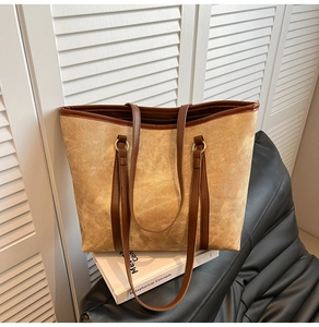 Détail d'un grand sac cabas jaune gingembre avec poignées en cuir marron posé sur un canapé