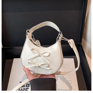 Vue détaillée du sac croissant blanc cassé avec nœuds décoratifs dans un coffret luxe
