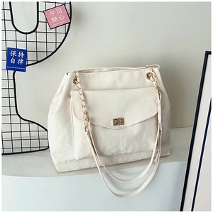 Detail of cream white tote bag featuring pleated texture and gold chain strap