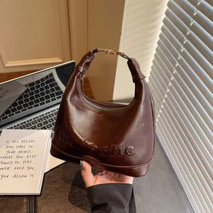 Brown oil wax leather bucket bag with hobo style and gold metallic buckle detail